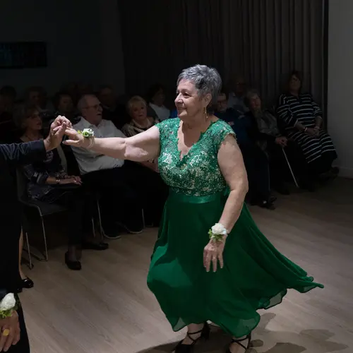 Senior woman in green dress is dancing with her partner / Une femme âgée en robe verte danse avec son partenaire.