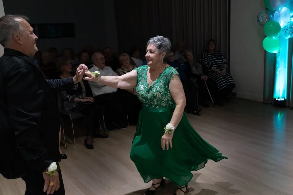 Senior woman in green dress is dancing with her partner / Une femme âgée en robe verte danse avec son partenaire.