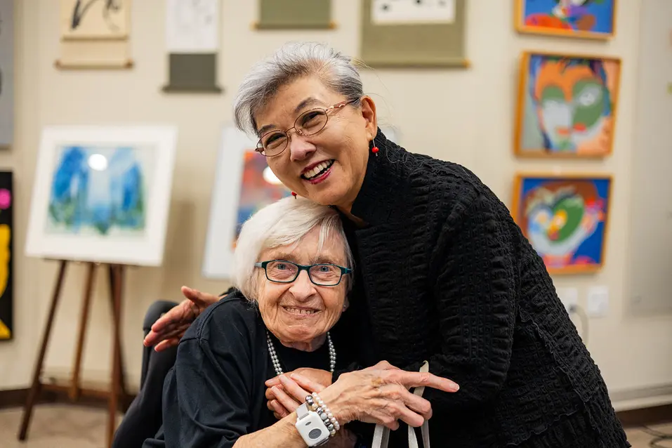 Senior women hugging each other at the art exhibition / Des femmes âgées s'étreignant lors d'une exposition artistique