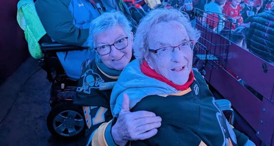 A group of seniors enjoying and cheering for hockey game at a stadium / Un groupe de personnes âgées s'amusant et encourageant une équipe de hockey dans un stade